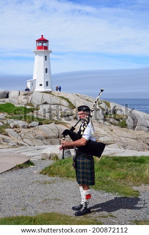 PEGGY\'S COVE NOVA SCOTIA JUNE 6: Man play bagpipe in front the lighthouse of Peggy\'s Cove a small rural community located on the eastern shore of St. Margarets Bay on june 6 2014.