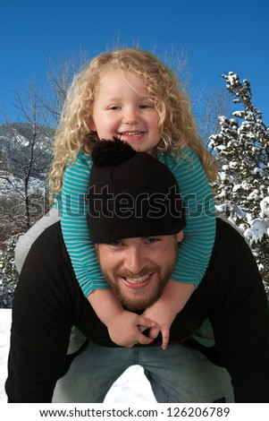 Young daughter riding piggyback on her father\'s shoulder.