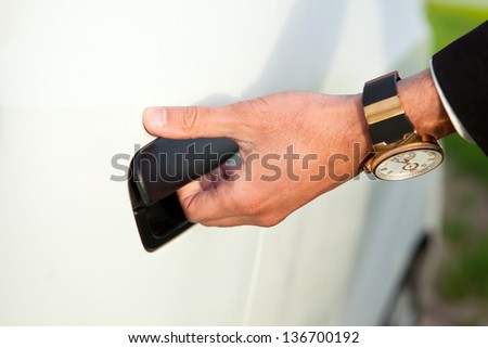 Businessman's hand opening door of his luxury car