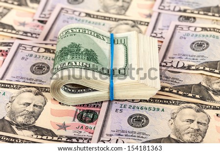 Folded dollar bills wrapped by rubber on money background
