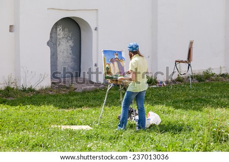 NOVGOROD, RUSSIA - JULY 23, 2014: Young artists paint at the walls of an ancient cathedral at the Yaroslav\'s Court in Veliky Novgorod