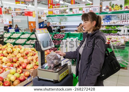 SAMARA, RUSSIA - OCTOBER 10, 2014: Young woman weighing potatoes on electronic scales in produce department of the Magnit store. Russia\'s largest retailer