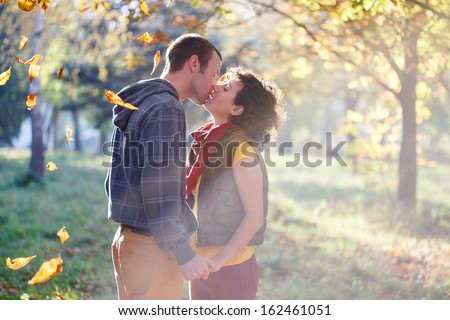 Loving couple kissing in the park in the sunlight on trees background