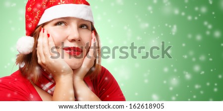 Young woman in new year or christmas suit smiling in thoughtful pose on green background with snowfall