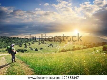 Tourist with a back pack on beautiful mountain and plain landscape with cloudy sky and sunlight