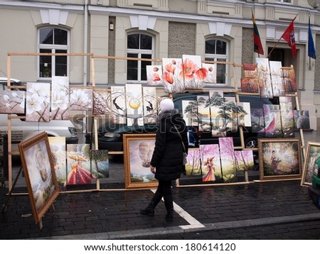 VILNIUS, LITHUANIA - MARCH 8 2014: A girl see to the paintings in Sventaragio street were is organized an annual traditional crafts fair - Kaziuko fair on March 8, 2014 in Vilnius, Lithuania