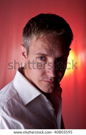 Young Man with serious look on red lit background