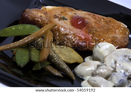 a mouth watering plate of food with meat in a sweet sauce with a cherry, accompanied by mushrooms and veggies