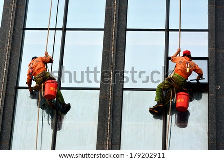 XIAMEN, CHINA - JANUARY 12: As a dangerous work, external wall cleaner is working on a building in Xiamen, Fujian Province, China in January 12, 2014. Xiamen is a developing city located in South of China.