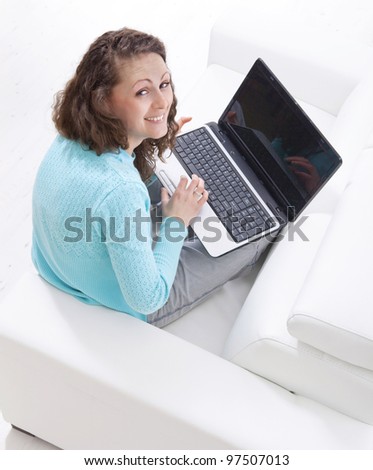 Happy young woman sitting on couch with a laptop