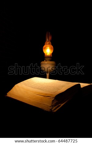 book with candle lamp on a black