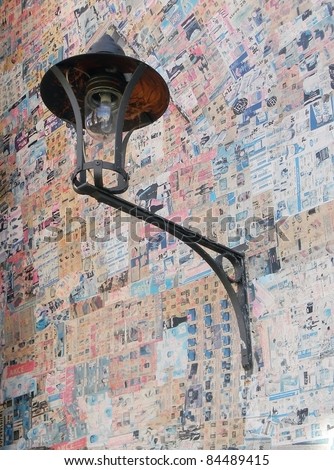 old wall plaster with color newspaper pages with historic black lamp