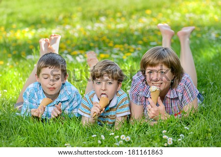 Happy family eat ice cream on a grass outdoors in spring park