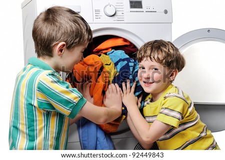 Funny boys loading clothes to washing machine.