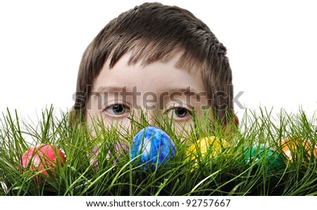 Easter egg hunt. Cute boy searching for easter eggs hidden in fresh green grass. Isolated on white background