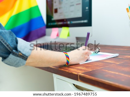 Woman's hand working in office with LGBT decor and accessories. Cultura LGBTQIA