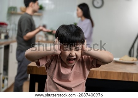 Young little Asian kid feel sad upset, boring while parent fighting arguing or quarrel, sad little boy frustrated with psychological problem caused by mom and dad family conflicts or violence concept. Foto stock © 