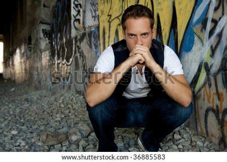 A young man kneeling down next to train tracks