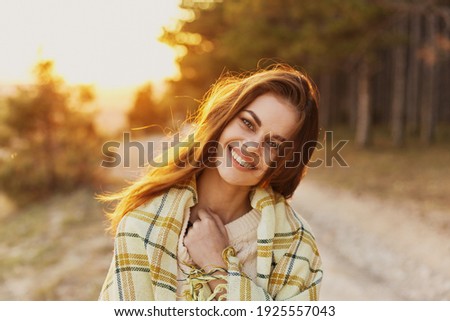 Happy woman with bread on her shoulders laughs front view and sunset in the background