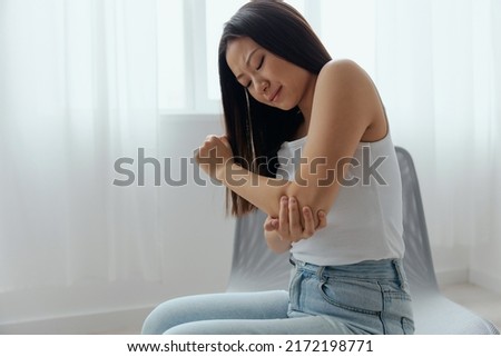 Tormented suffering tanned beautiful young Asian woman hurting holding painful elbow at home interior living room. Injuries Poor health Illness concept. Cool offer Banner Stock foto © 