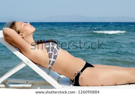 The cute girl on a plank bed at the sea