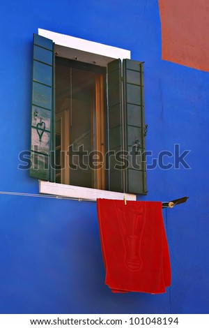 Colorful blue house facade with red towel. Island Burano near of Venice, Iialy.