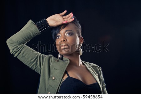 Portrait of african american woman, looking away and protecting her face with her hand against light, isolated over black