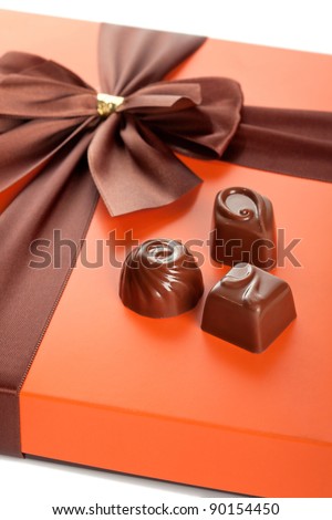 Chocolate sweets and beautiful gift box with ribbon bow, closeup shot