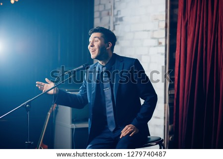 Stand up comedian on stage. Young man talks joke into microphone or sings songs. Stockfoto © 