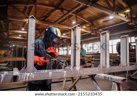 Factory industrial weld worker in workplace with spark. Professional welder erecting metal steel. Сток-фото © 