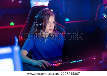 Similar – Image, Stock Photo Teenager girl playing video game at home. Gamer playing online in dark room lit by neon lights. Competition and having fun