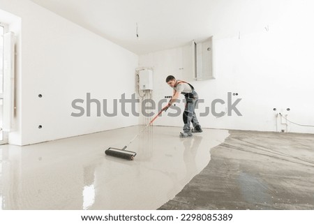 Worker use screed concrete epoxy for level. Leveling with mixture of cement for floors. Foto stock © 