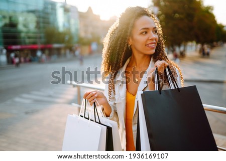 Fashion woman with shopping bags walking on street. Spring Style. Consumerism, sale, purchases, shopping, lifestyle concept.