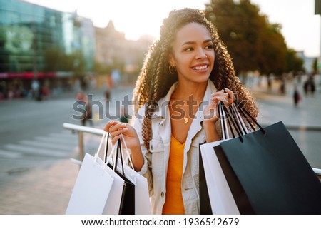 Fashion woman with shopping bags walking on street. Spring Style. Consumerism, sale, purchases, shopping, lifestyle concept.