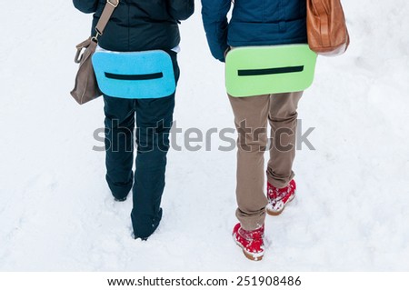 People walk with a camping mat for sitting in the snow.