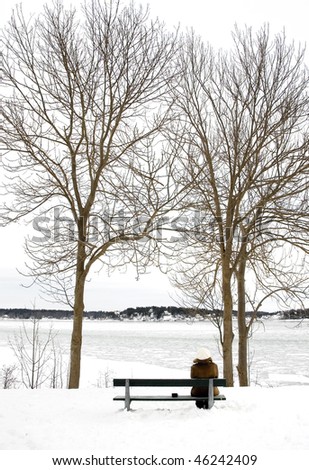 A girl is sitting in the snow having a cup of coffee.