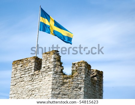 A Swedish flag flying over a medieval wall on Gotland