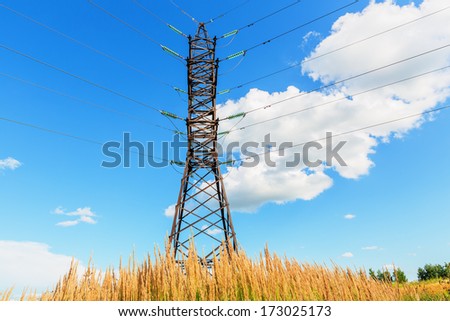High voltage line beneath the blue sky with cumulus clouds