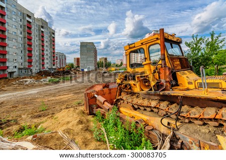View of construction site (bulldozer and houses beneath cloudy sky)
