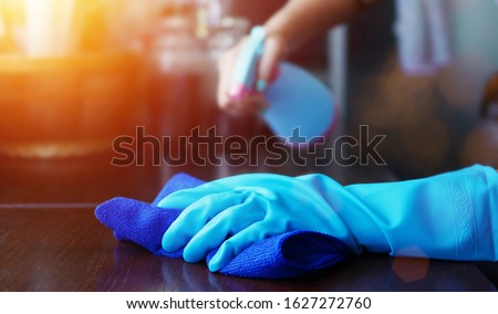 hand in blue rubber glove holding blue microfiber cleaning cloth and spray bottle with sterilizing solution make clean and disinfection for good hygiene 商業照片 © 