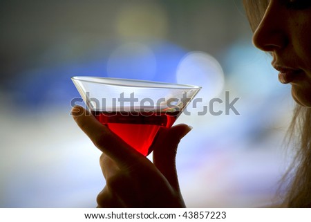 The girl is holding in his hand a glass of alcoholic beverage, red wine in glass
