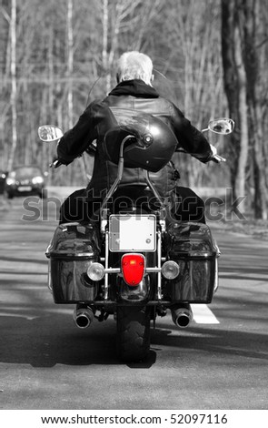 A man is riding a motorbike on the forest road (view from behind)