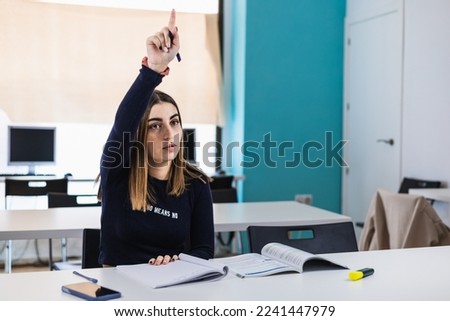 young woman student raising hand and asking question to professor during class in college Foto stock © 
