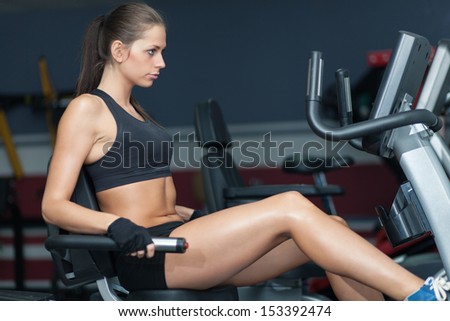 Sportive woman doing exirsise on cycling simulator in the sport club