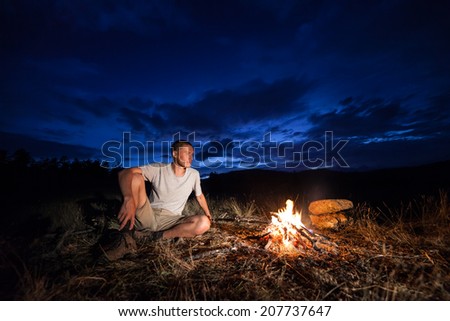 Man and campfire at night. Tourist looking at fire