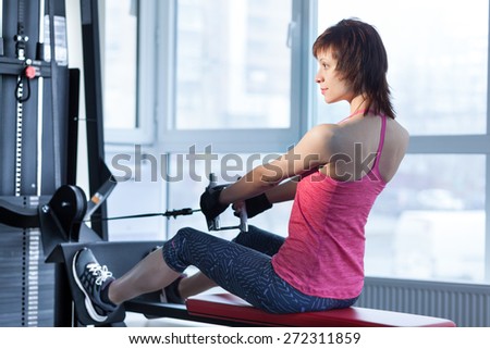 Woman doing exercise with pull-down machine at the gym