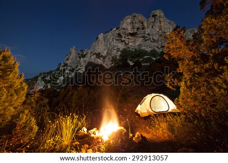 Tent and campfire near mountain at night