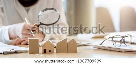 Looking for real estate agency, property insurance, mortgage loan or new house. Woman with magnifying glass over a wooden house at her office Imagine de stoc © 