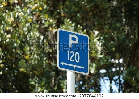 'P 120' blue with white writing parking sign which the arrow indicates the direction you can park in for any vehicle can park for 120 minutes at the street. Parking sign with Blurred tree background. Stock fotó © 