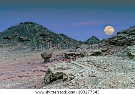 Classical biblical landscape with rise of supermoon in desert of the Negev, Israel
